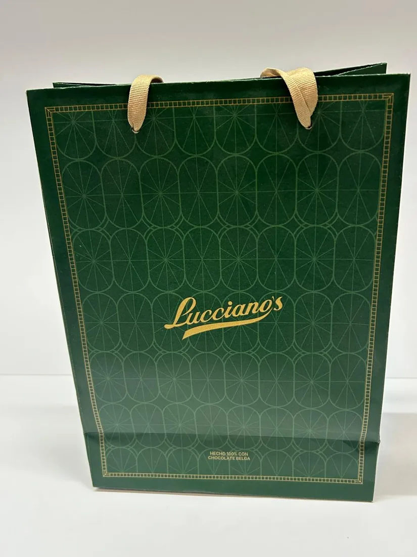 Bolsa de papel verde con guarda dorada y manijas de cinta